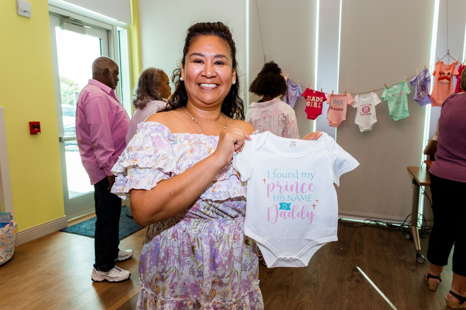 A guest shows off a white baby onesie at a celebratory shower event.