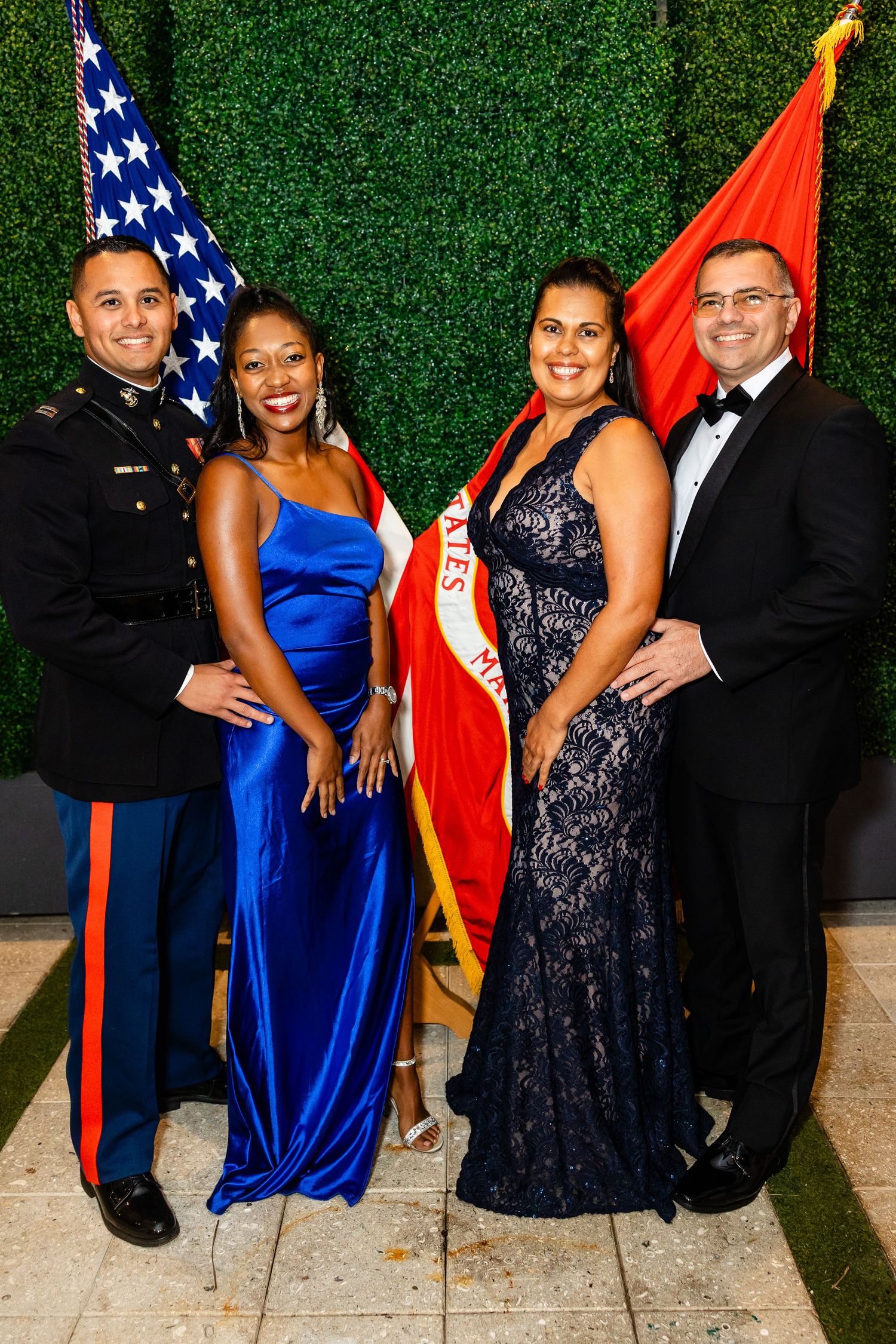 Military service members and guests pose in formal attire with American flags at an elegant event.