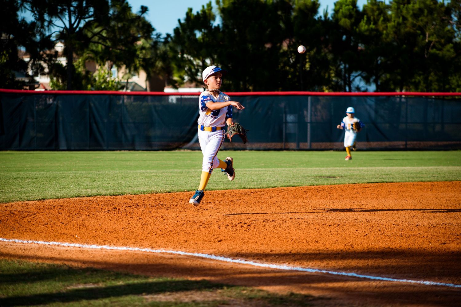 Baseball player running down the first base line after hitting during a game on a sunny day.