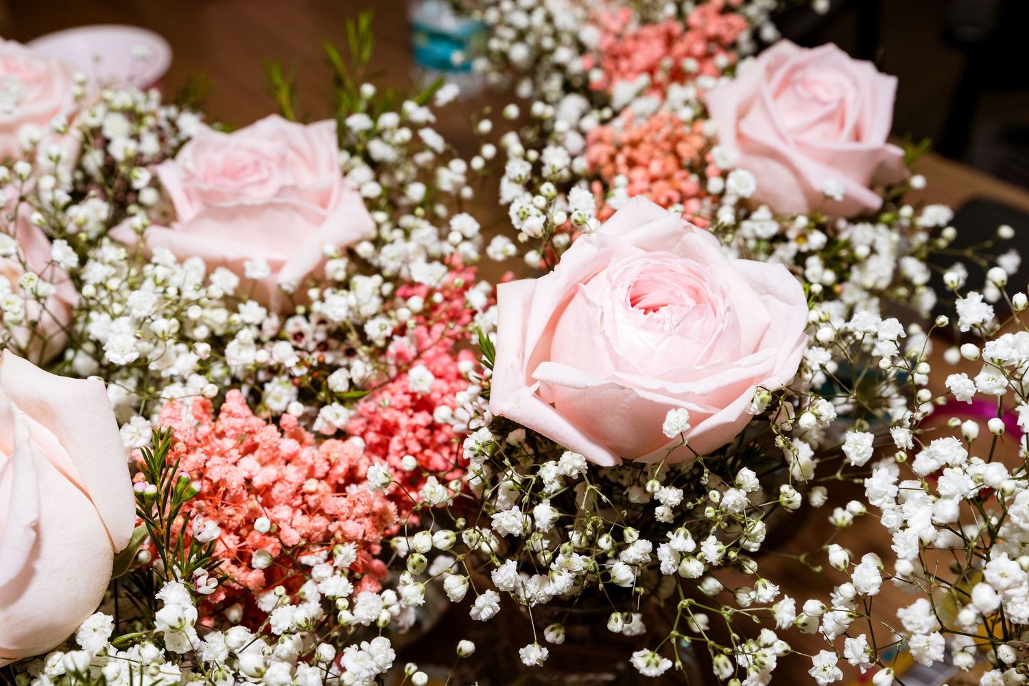 Pink roses and baby's breath flowers in a delicate floral arrangement.