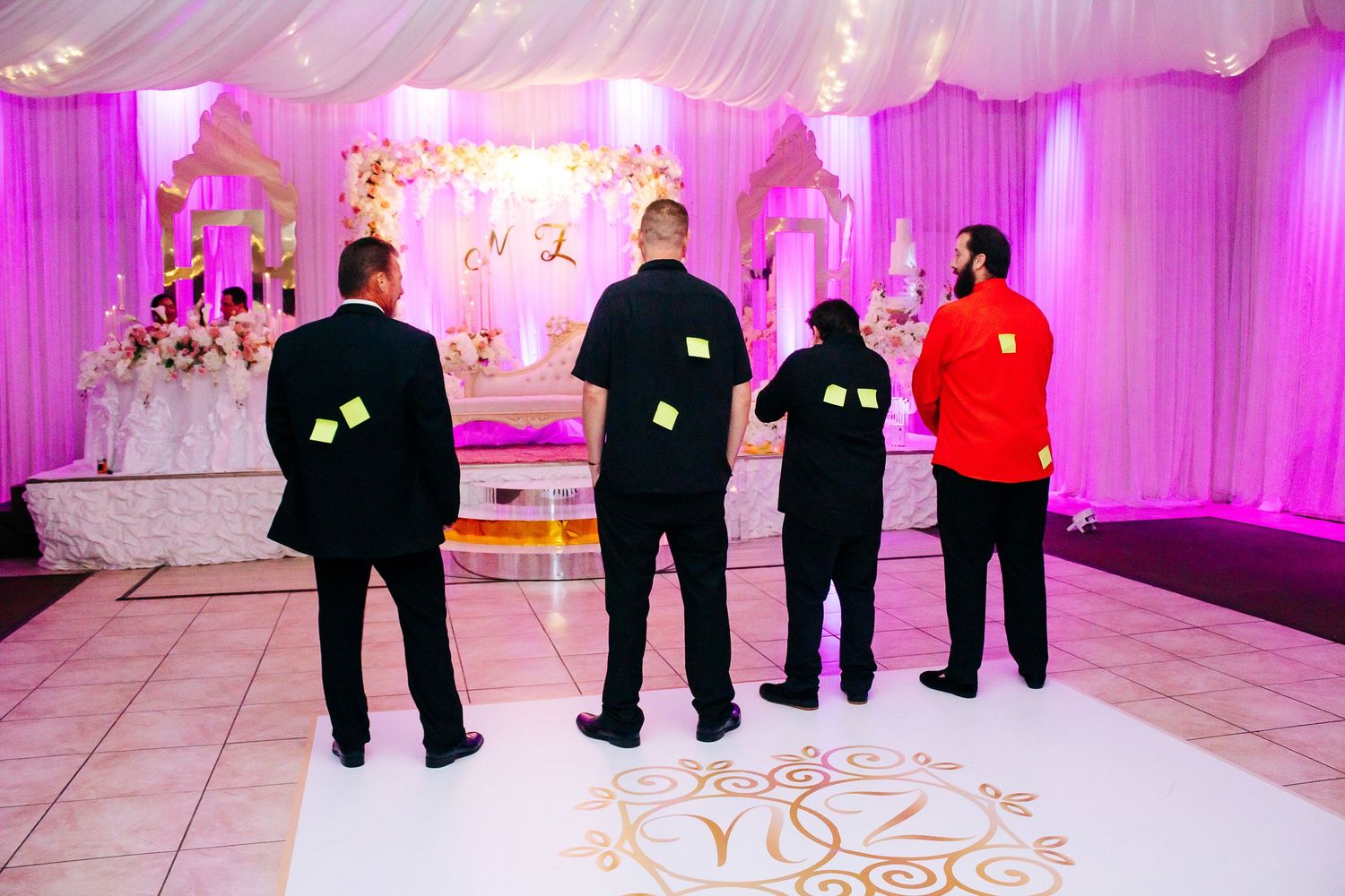 Elegant wedding reception venue with pink uplighting and draped white fabric ceiling.