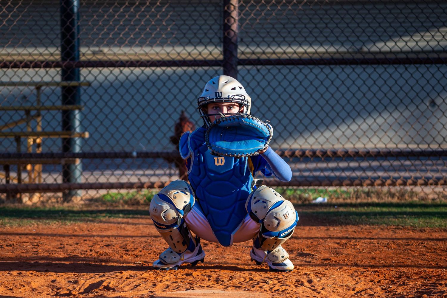 Baseball player in blue uniform slides into base during competitive game on dirt infield.