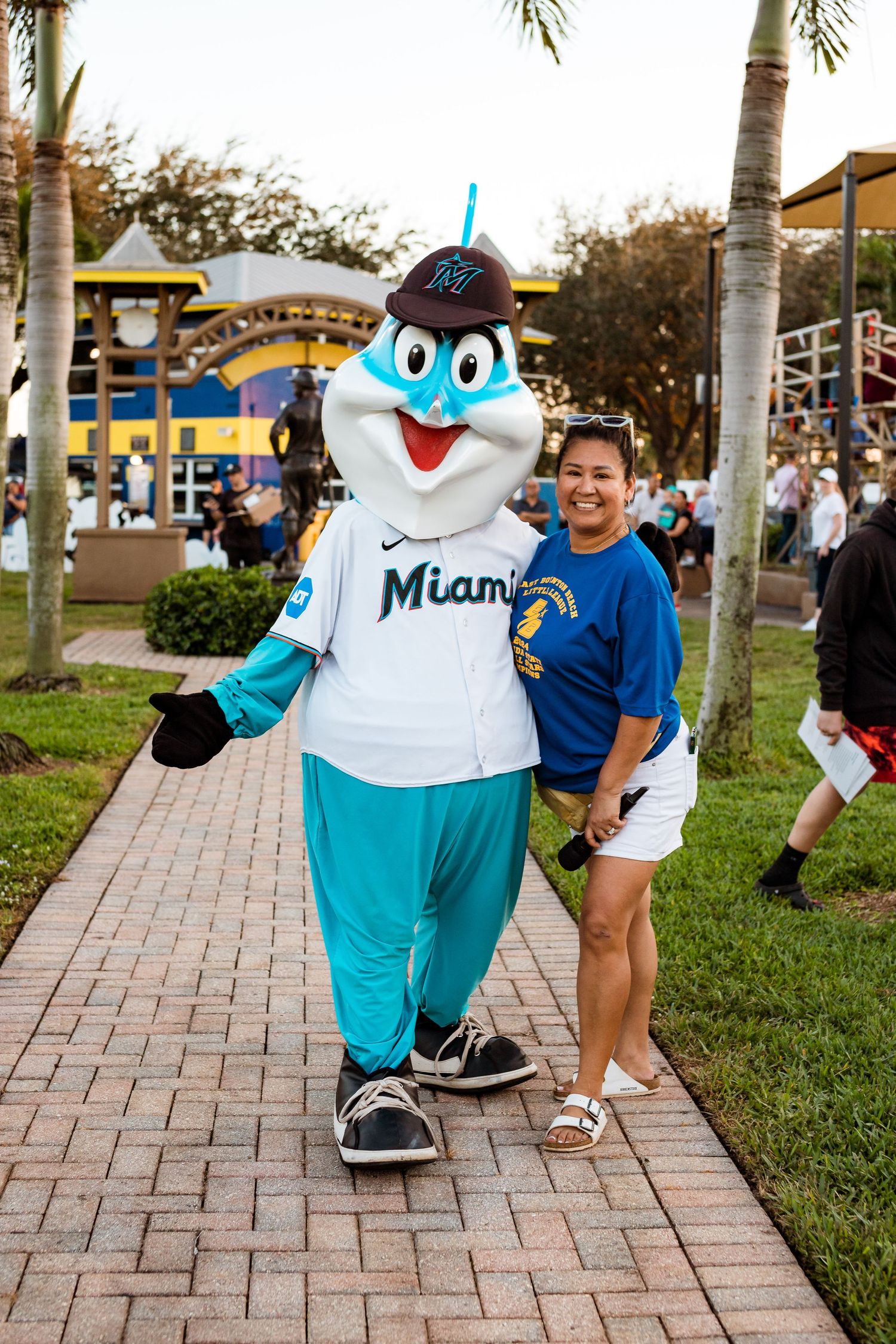 Miami Marlins mascot Billy poses with fan on brick pathway at ballpark.