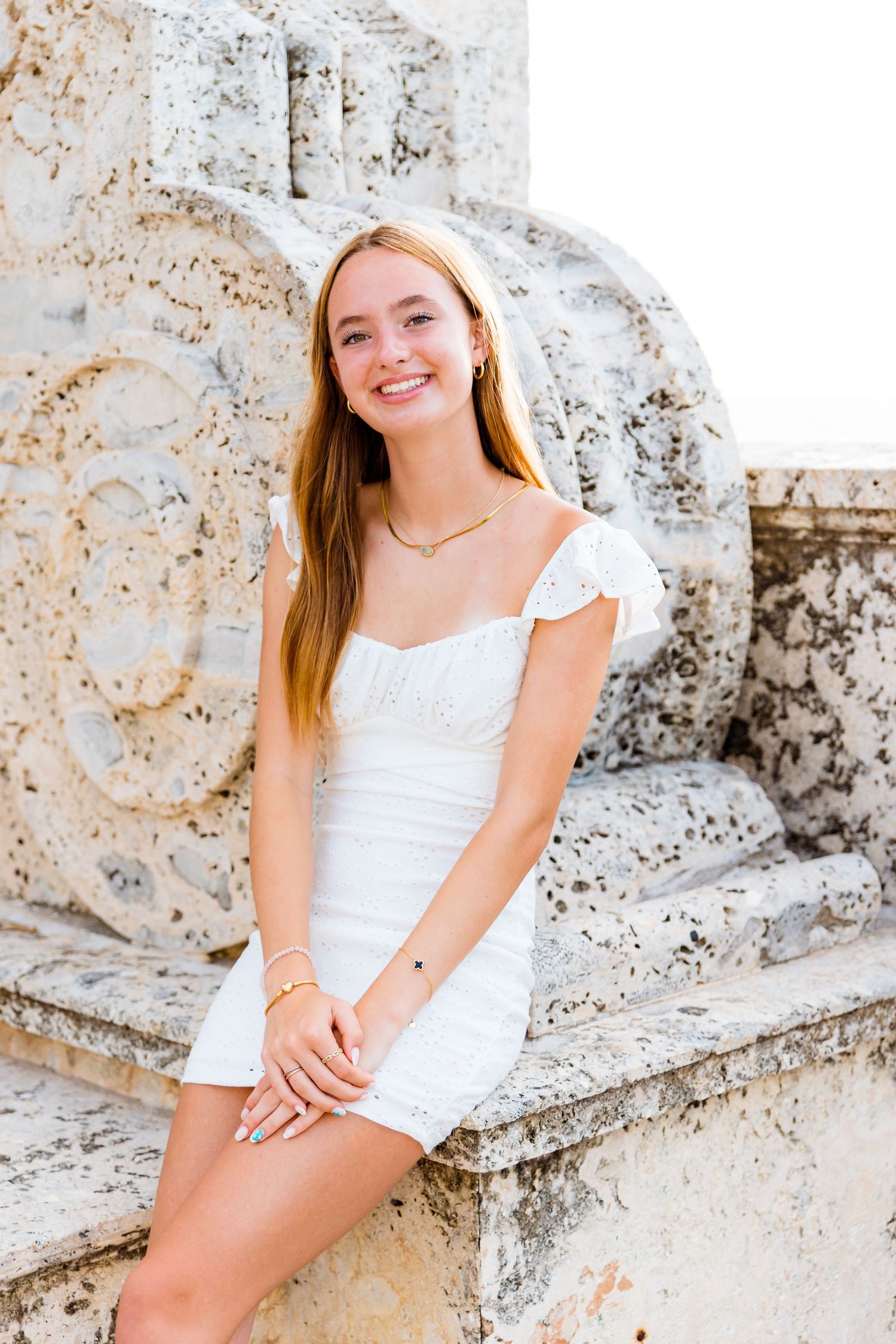 A summer portrait featuring a white dress against antique stone architecture in a Mediterranean setting.
