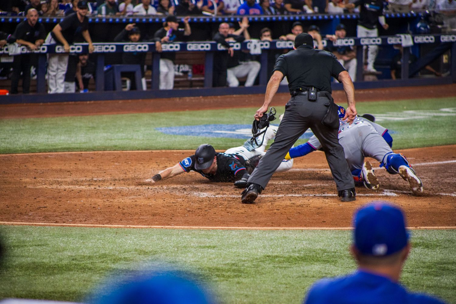 Baseball players colliding at home plate during intense game action.