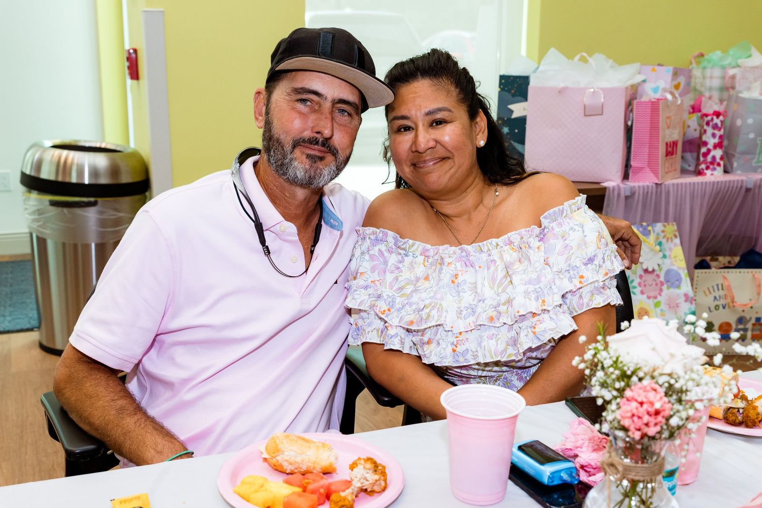 A couple enjoying a celebration with table decorations and flowers at what appears to be a baby shower.
