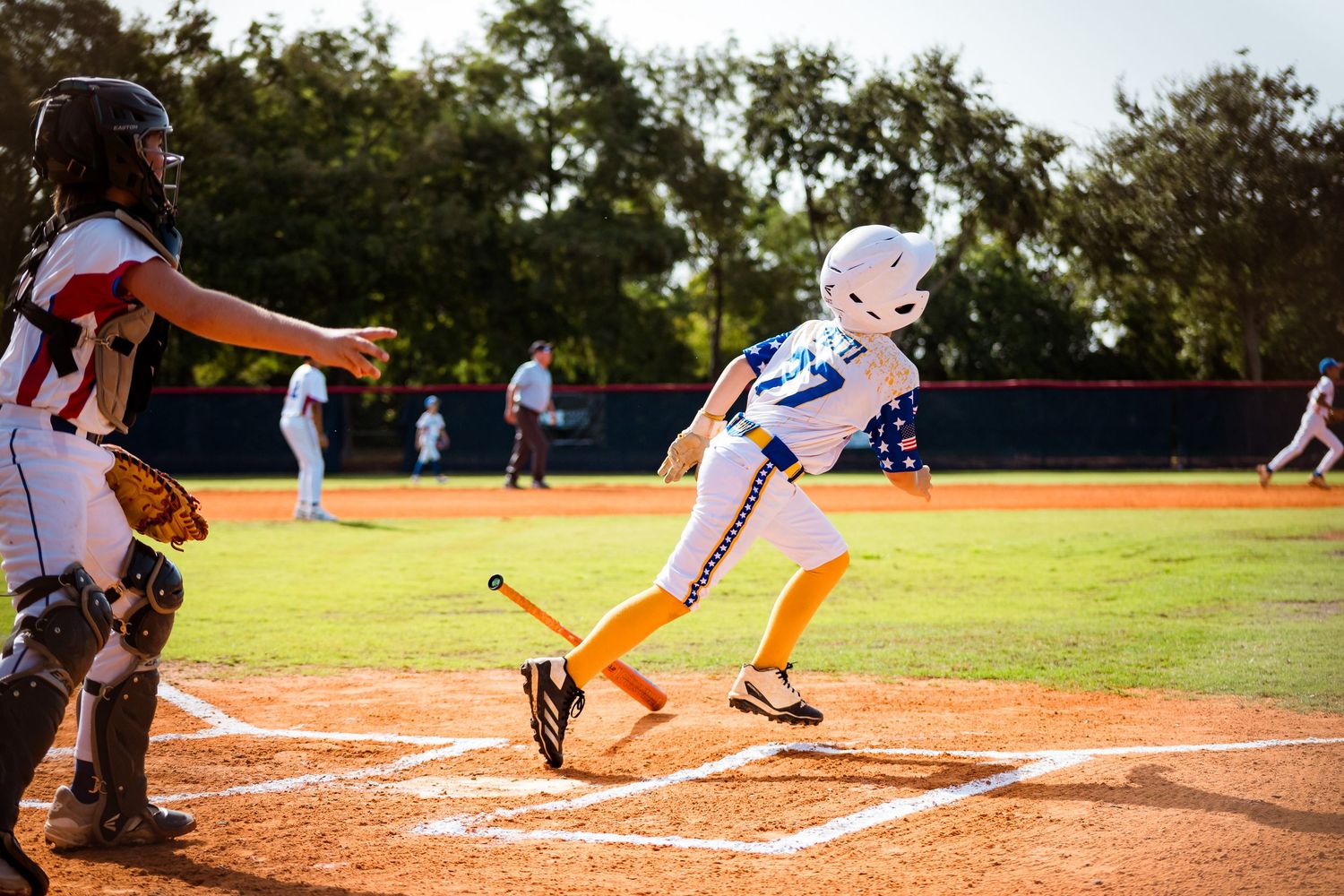 Close-up view of baseball player at bat with catcher and umpire at home plate during daytime game.