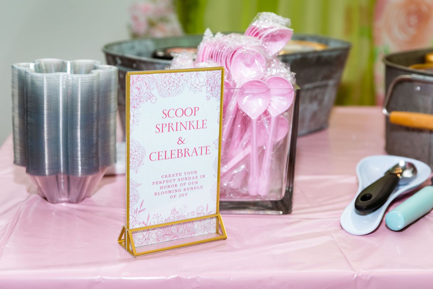 Pink and gold party table setup with a 'Scoop & Sprinkle' sign and decorative elements.