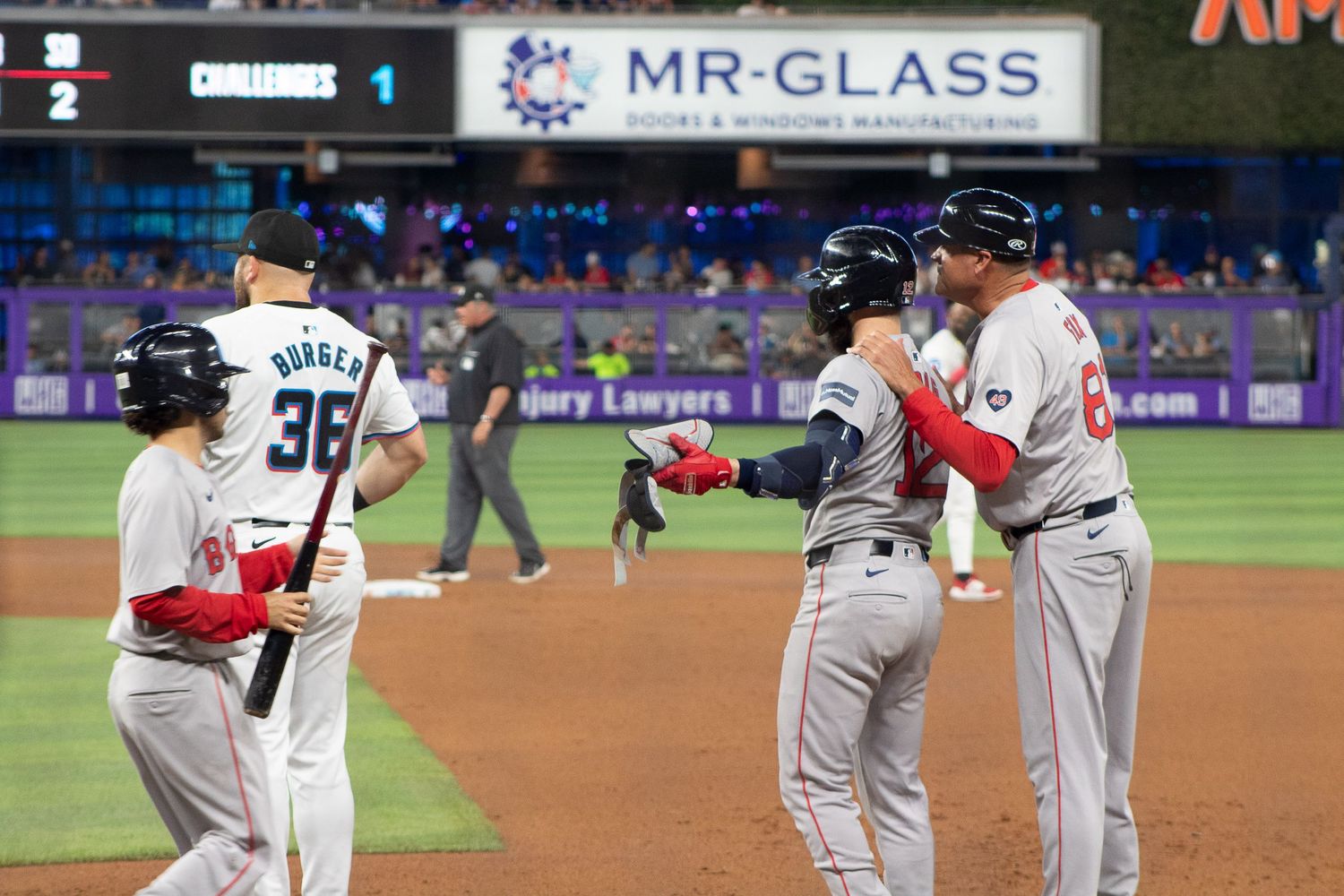 Baseball players gather on the field during a game, with stadium signage visible in the background.