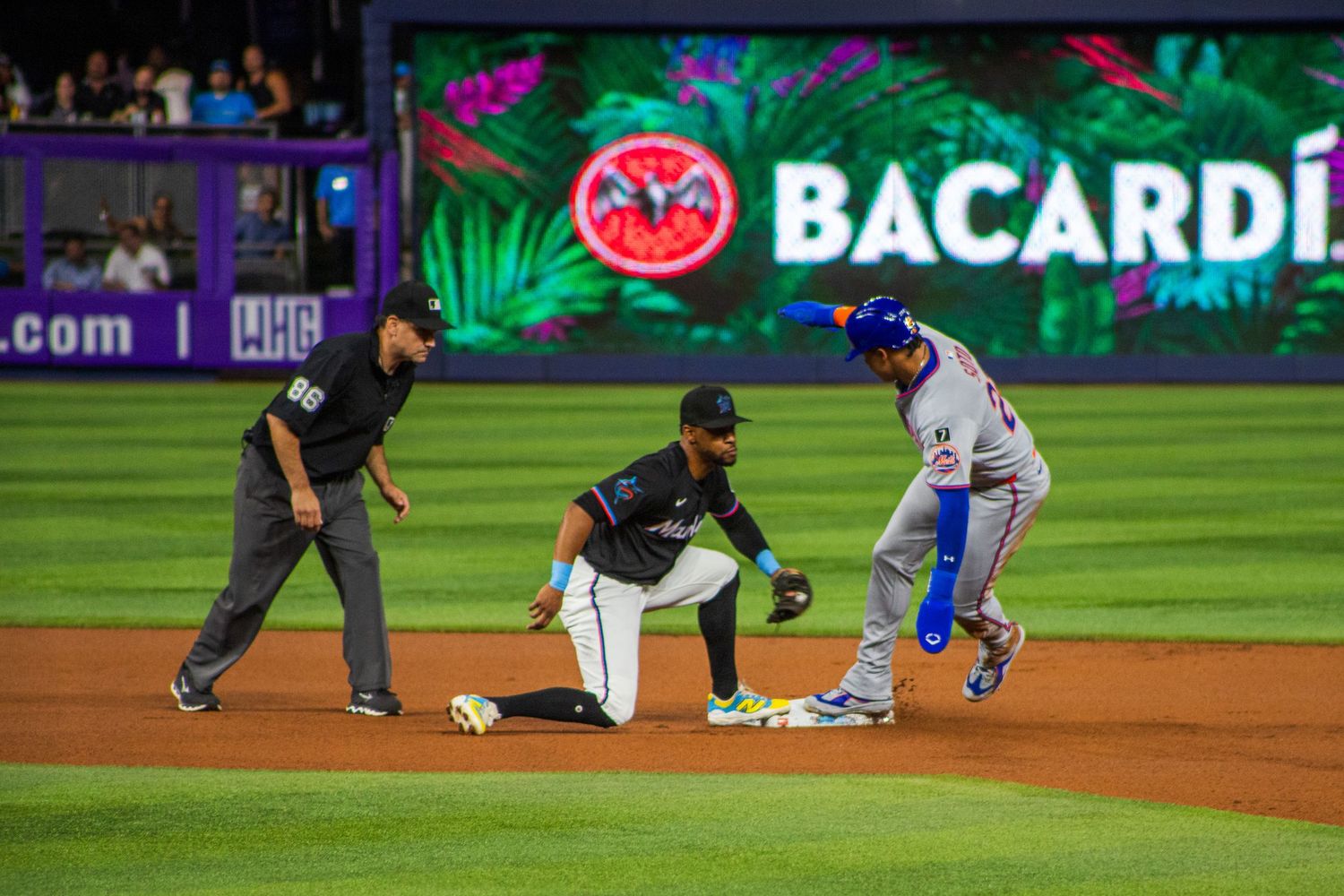 A baseball player slides into second base during a night game at a professional baseball stadium.