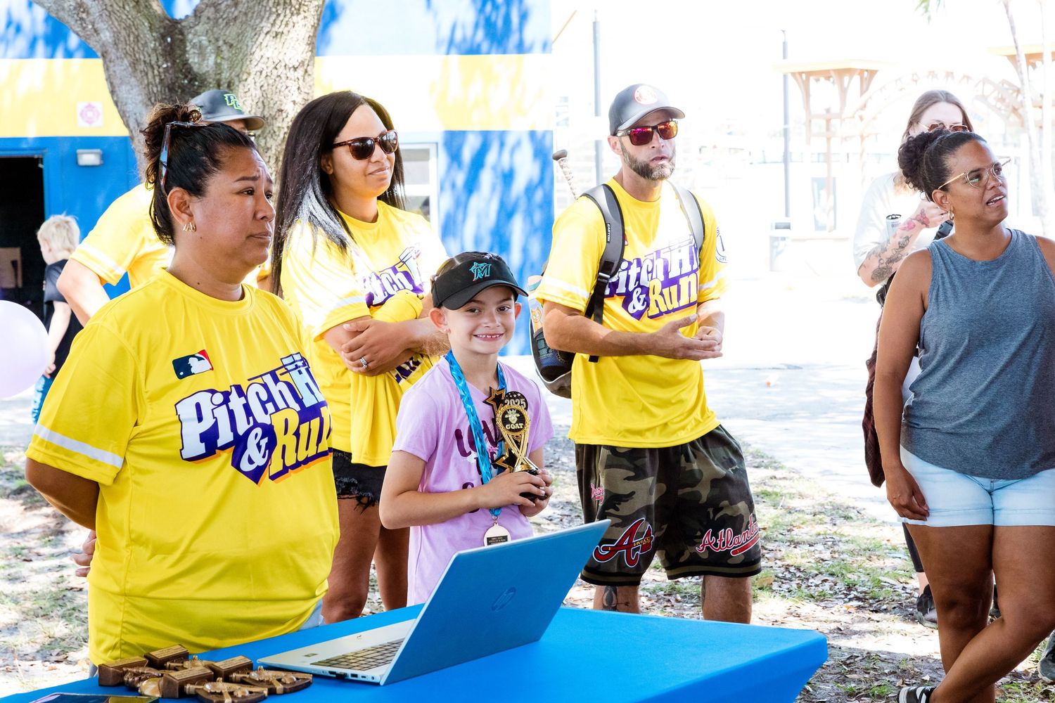 People in bright yellow shirts gathering outdoors at a casual community event.