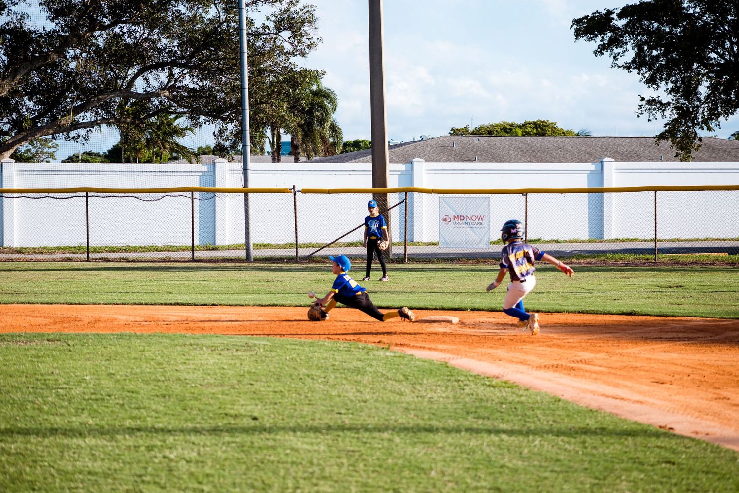 Youth baseball pitcher in mid-throw motion on pitcher's mound during daytime game.