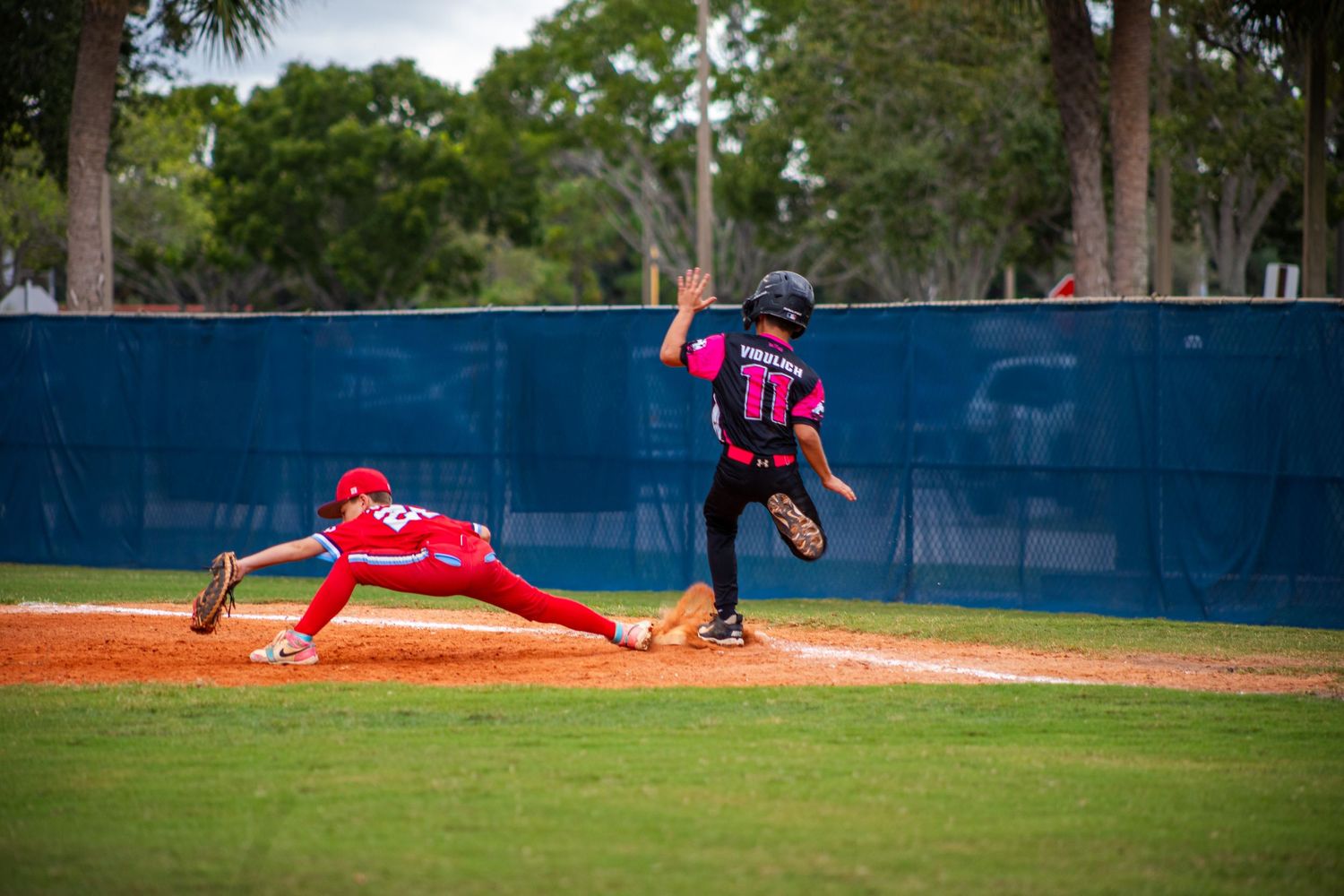 Baseball player sliding into base during competitive play on sunny afternoon.