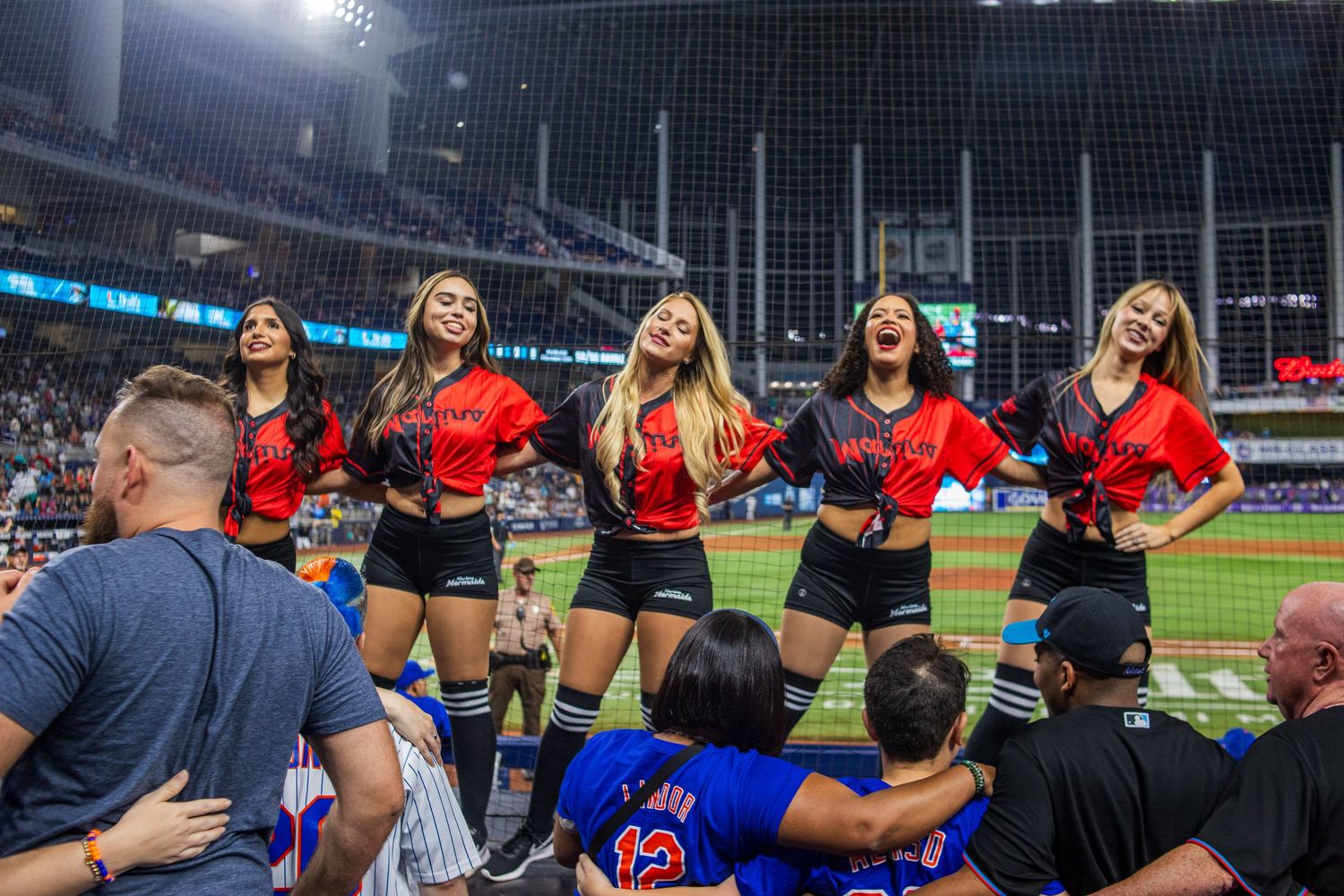Baseball players and performers gather on the field at a stadium during a special event celebration.
