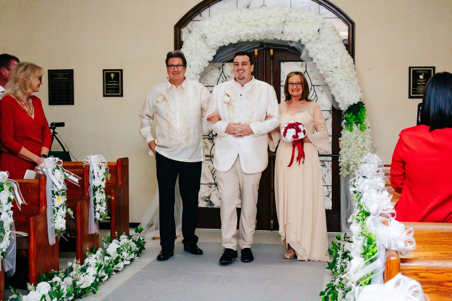 A panoramic view of a traditional church wedding ceremony with guests, floral decorations and white-clad attendees.