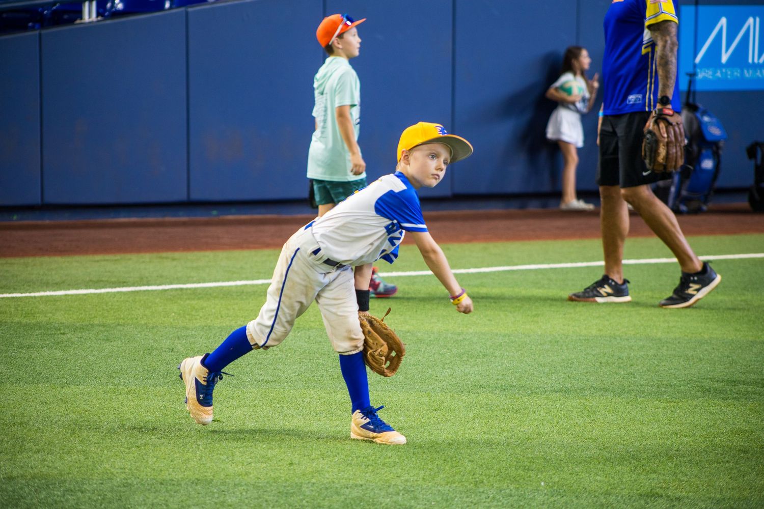 Young player in a blue and white baseball uniform practices pitching form on the field.