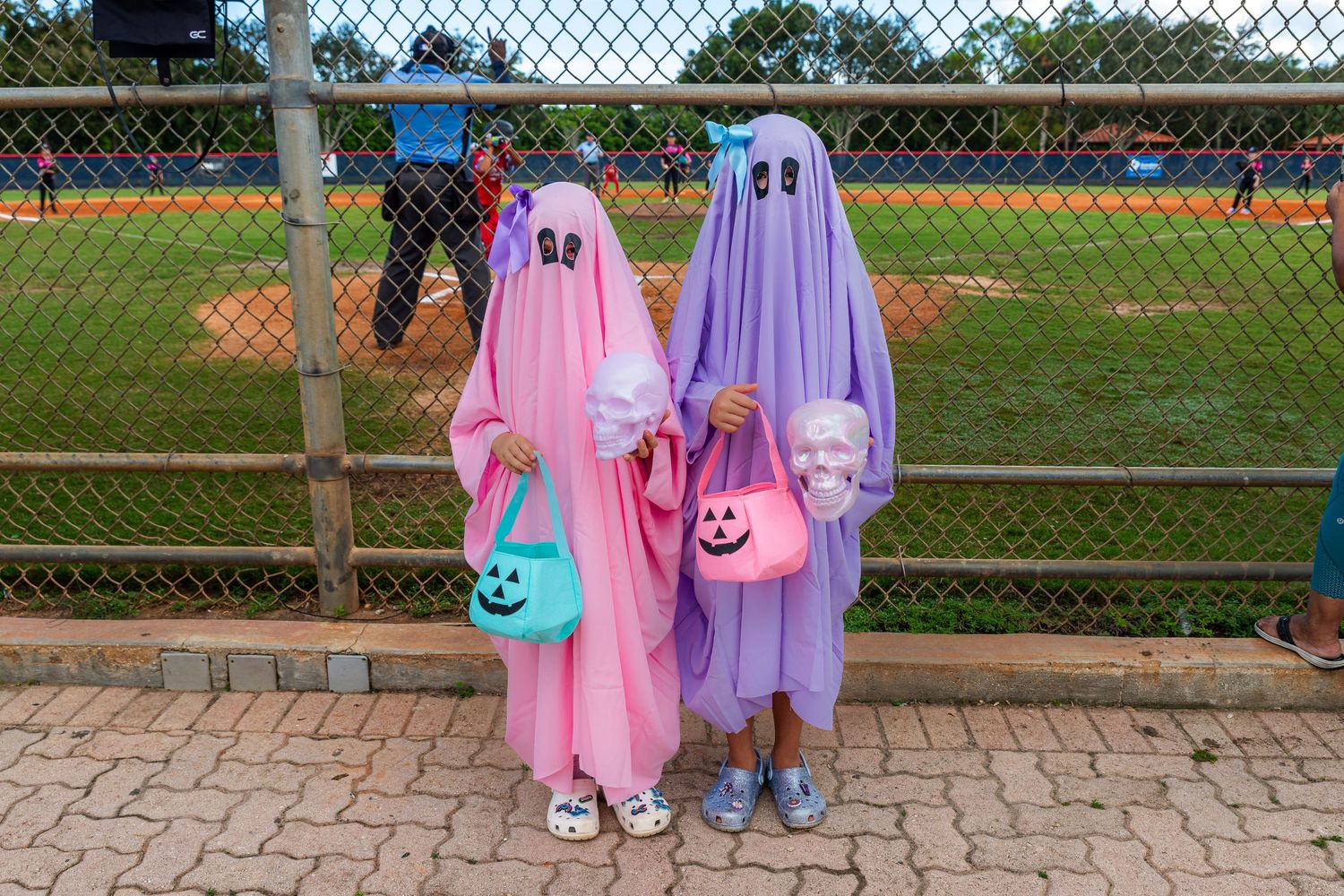A group of people wearing colorful ghost costumes walk along a path at an outdoor event.