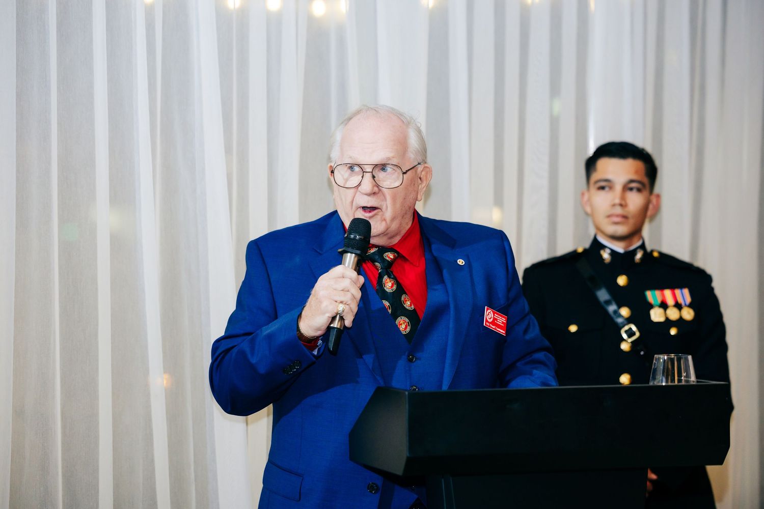 Guests in formal attire and military dress uniforms gathered at an elegant reception.