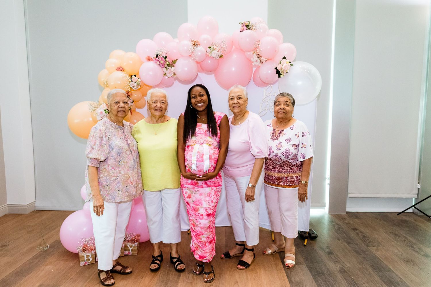 Balloon arch with pink and peach balloons decorating indoor party space.