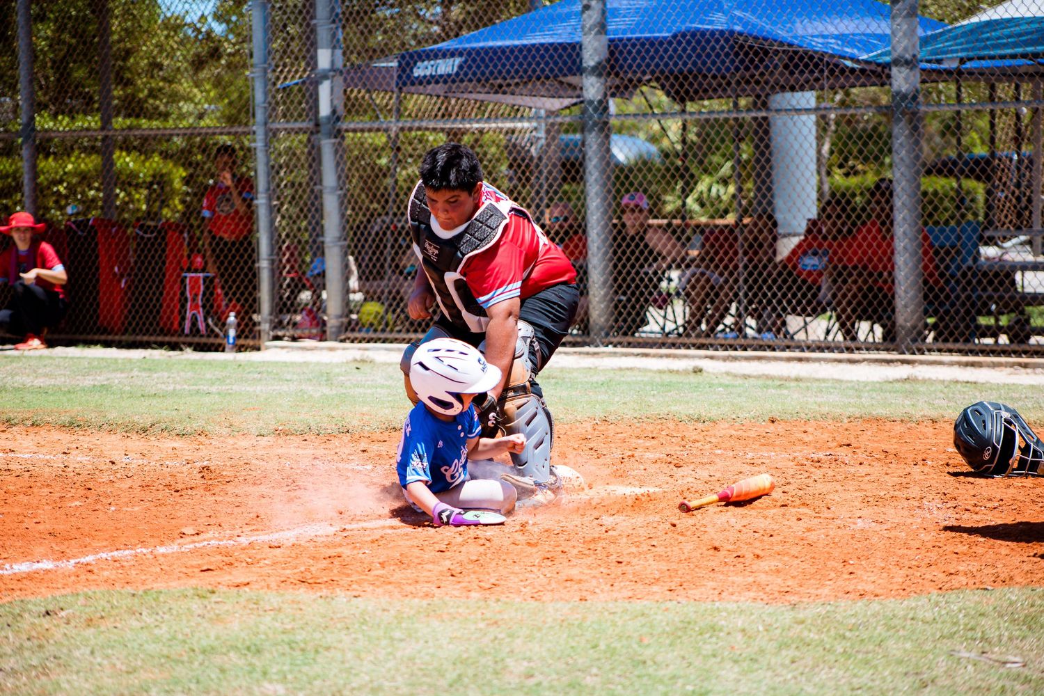 Catcher in protective gear crouches behind home plate during baseball game.