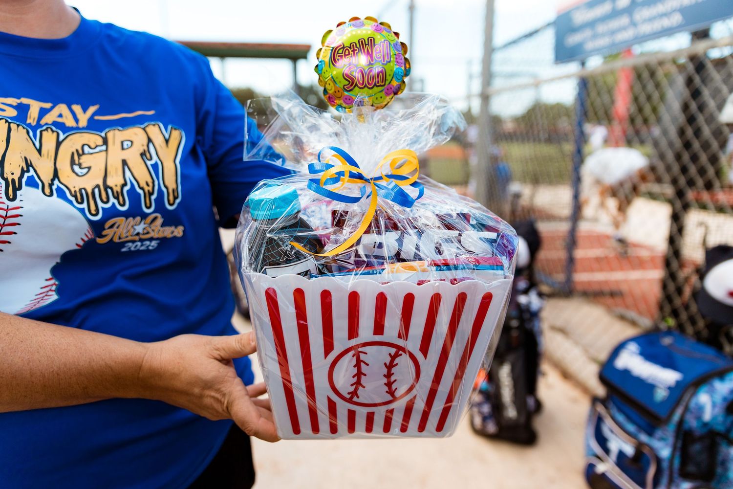 A series of striped popcorn containers filled with baseball-themed snacks and treats arranged side by side.