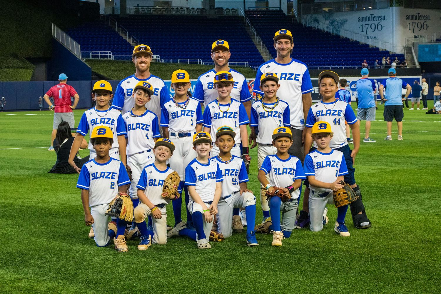 Youth baseball team in blue and white uniforms posing for group photo on field.