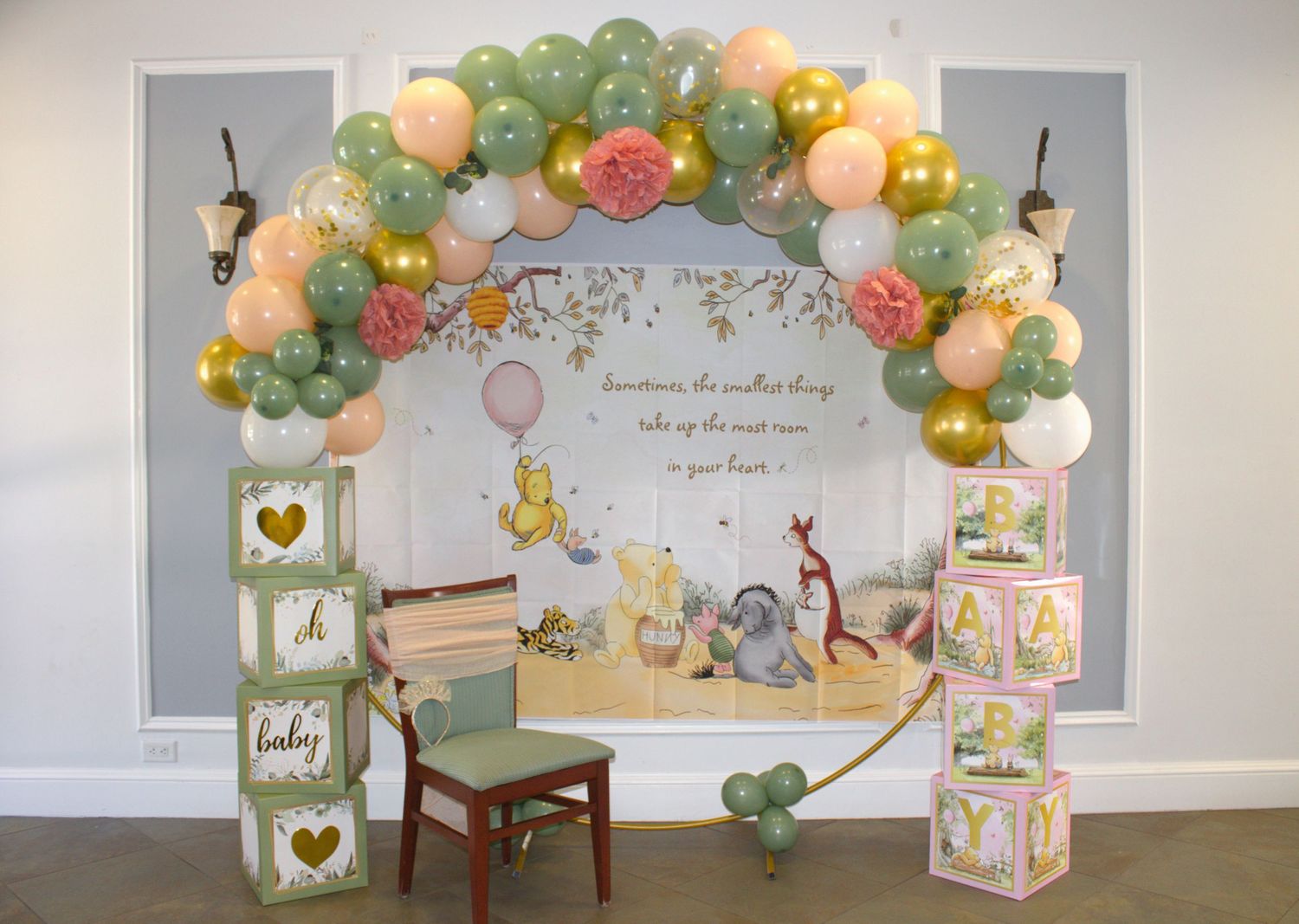 Classic Winnie the Pooh themed baby shower backdrop with pastel balloon arch and decorative blocks.