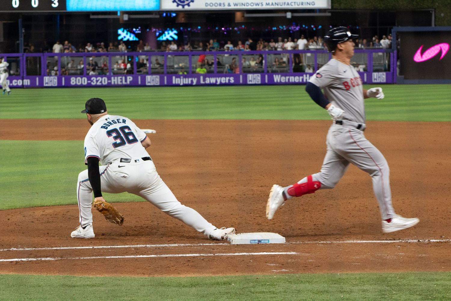 First baseman stretches to make play as runner approaches base during baseball game.