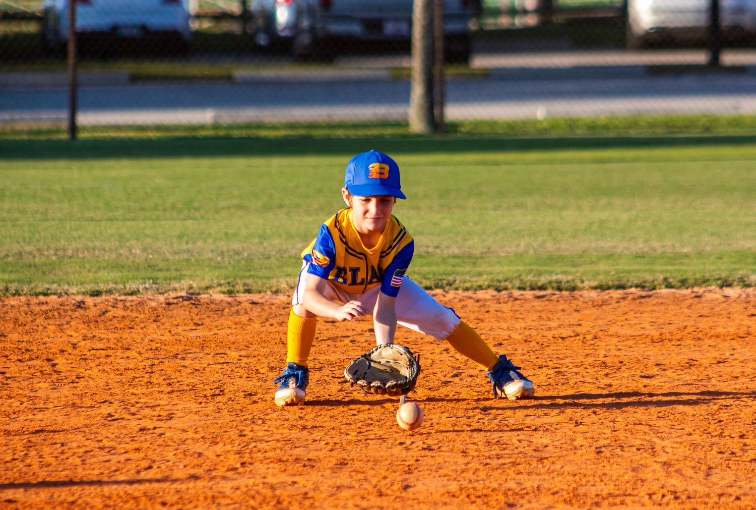 Baseball player sliding into base during game on orange dirt infield.