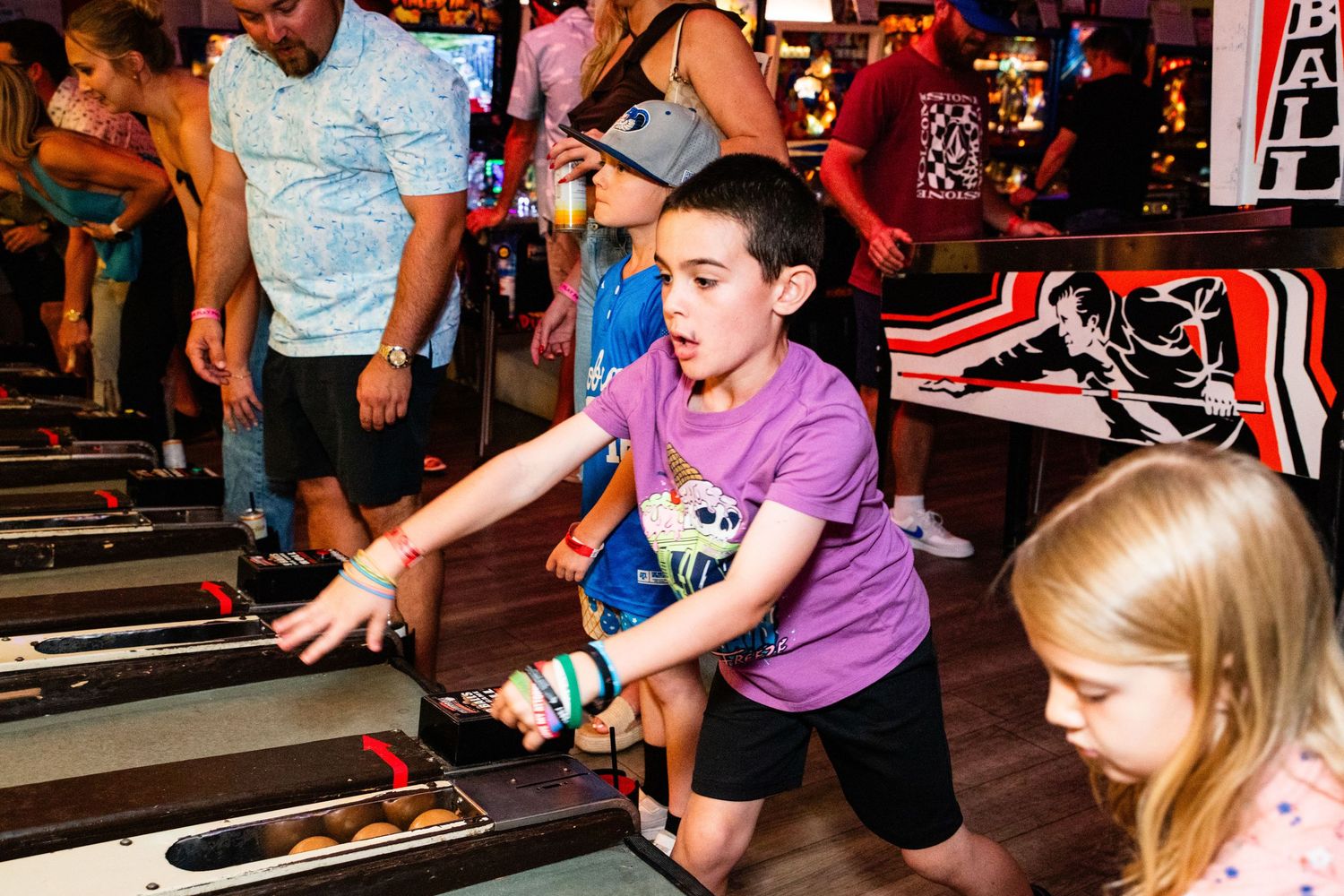 A group of people, including children, playing an arcade game together.