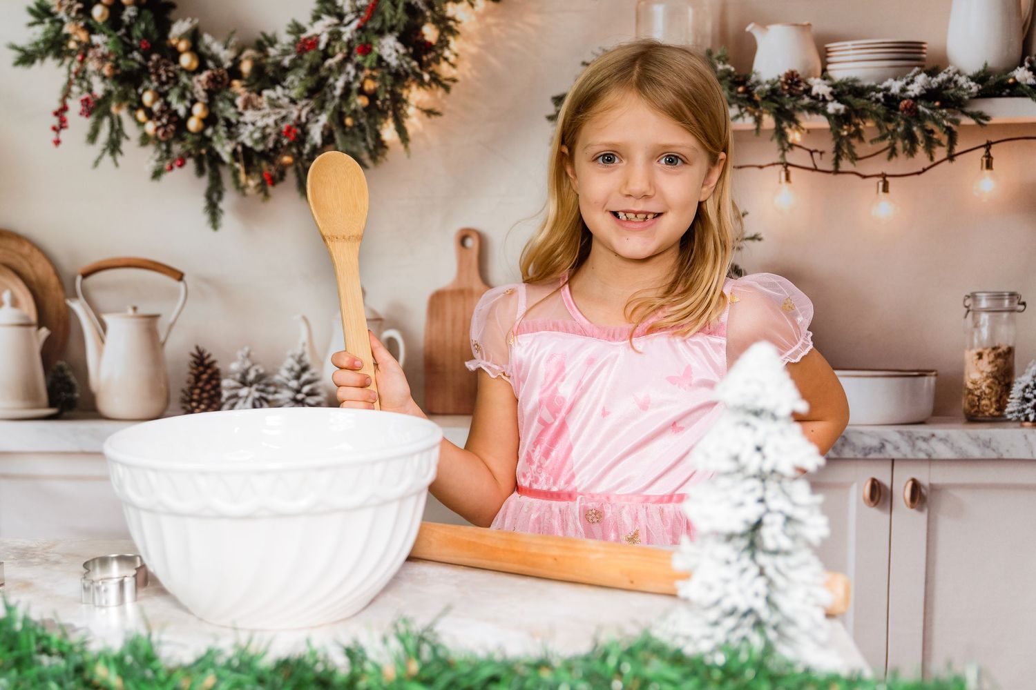 A festive kitchen decorated for Christmas with greenery, white decor, and twinkling lights creating a cozy holiday atmosphere.