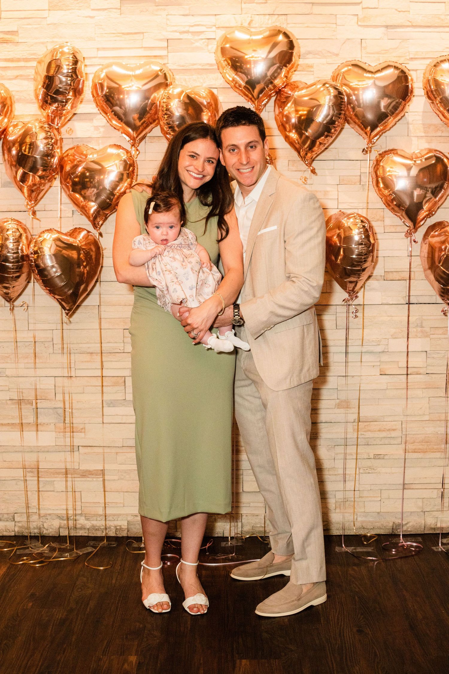 Elegant family photo against a backdrop of metallic heart-shaped balloons.