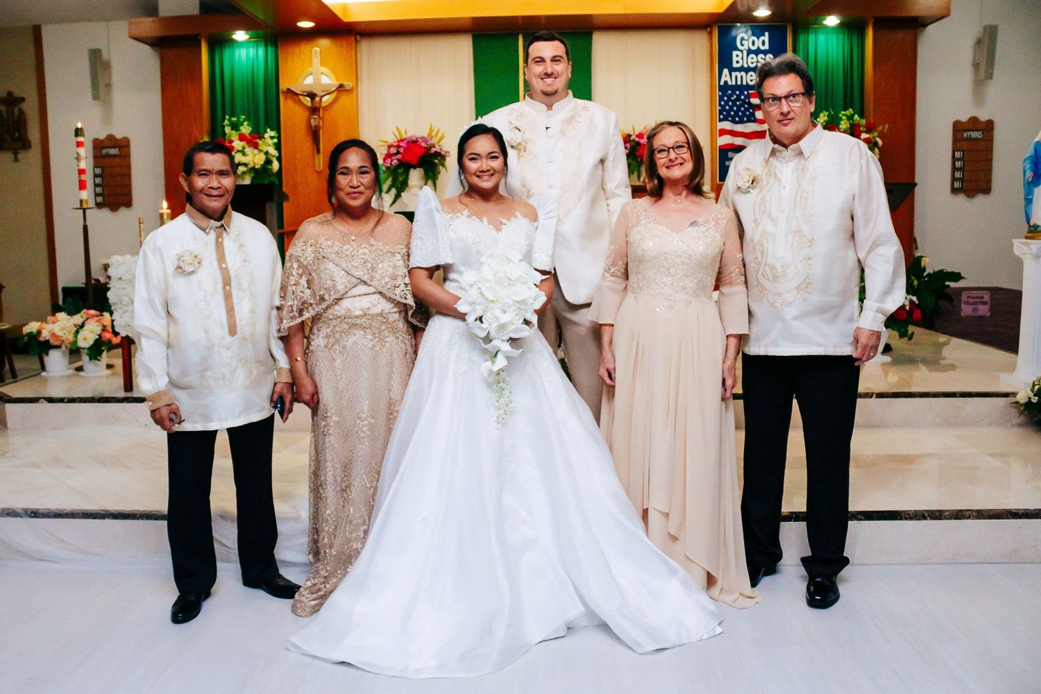 Wedding party poses with family members in formal attire at church altar.