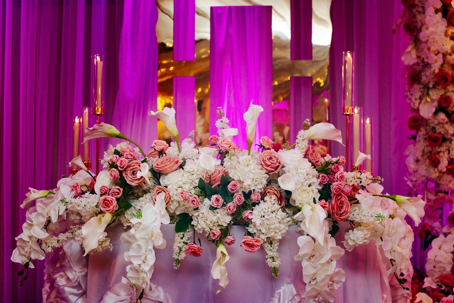 Luxurious floral arrangements with white and pink blooms against purple-lit backdrop.