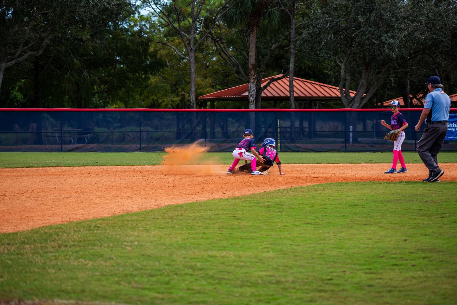 A baseball game in progress on a sunny day with players on the field and spectators in the background.