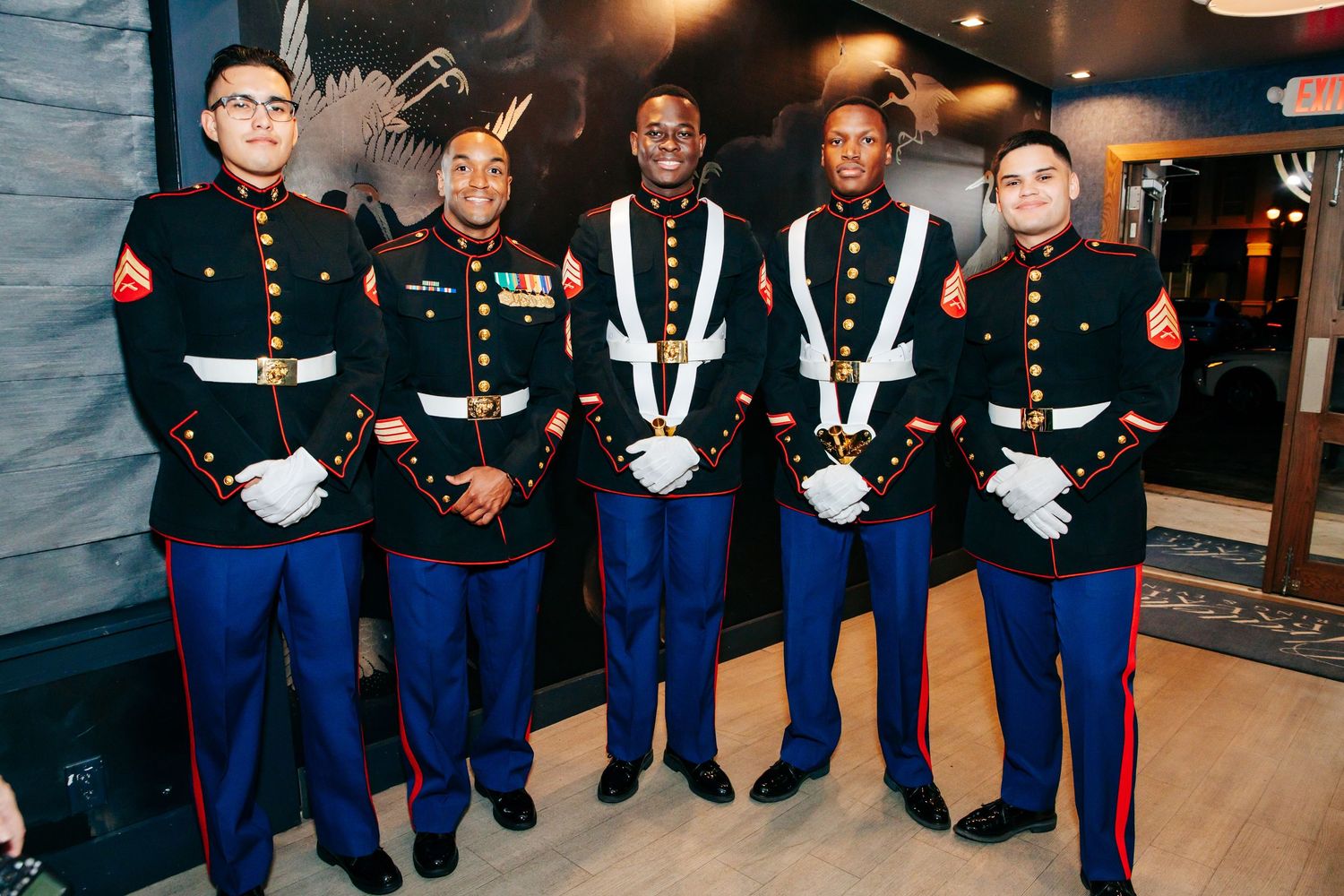 A group of Marines in dress uniforms stand together for a formal photograph.