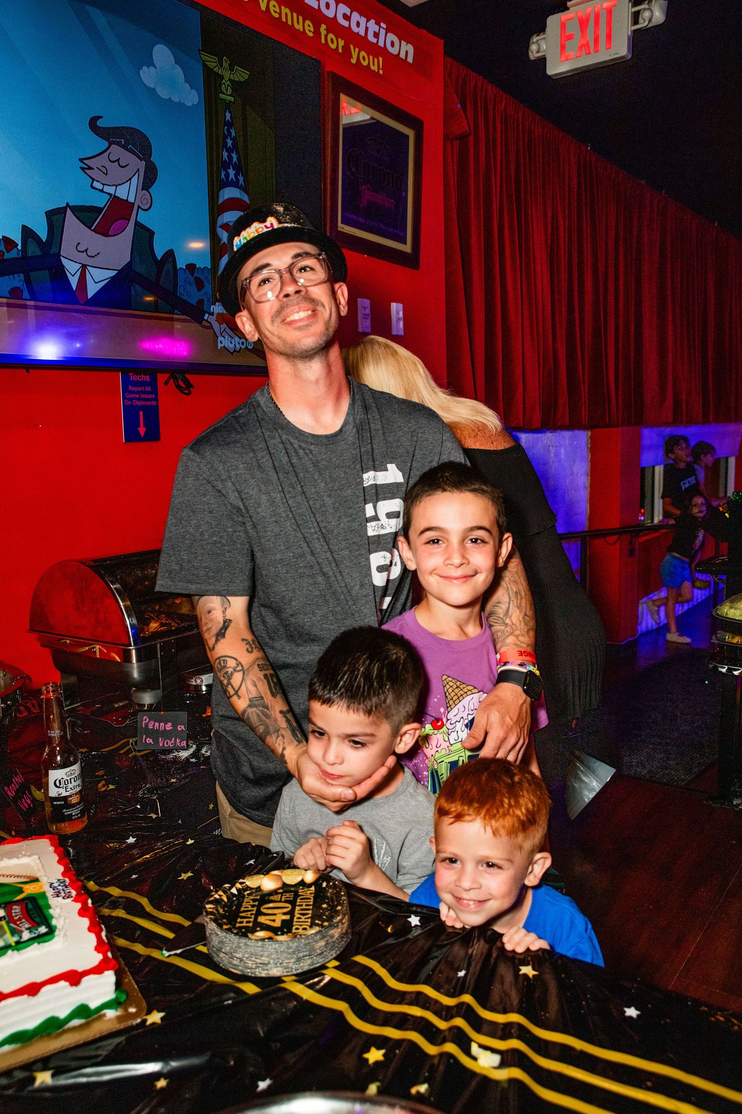 A family celebrating a birthday together, with a cake and presents on a table in front of them.