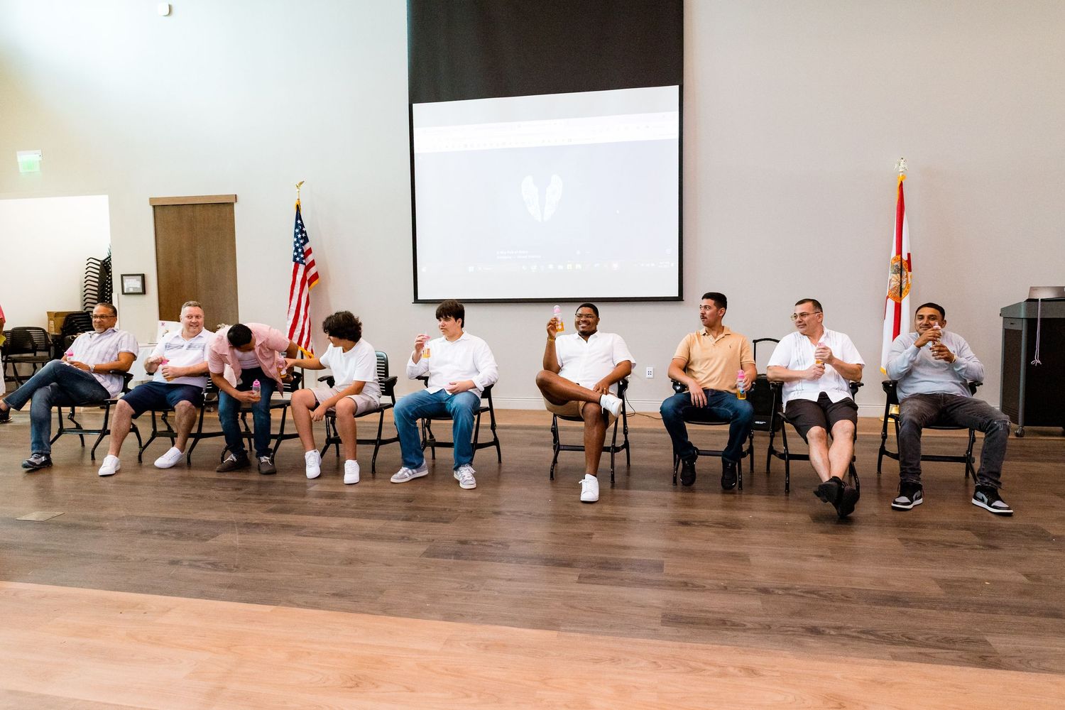 Row of chairs arranged for presentation with American flag and projection screen in background.