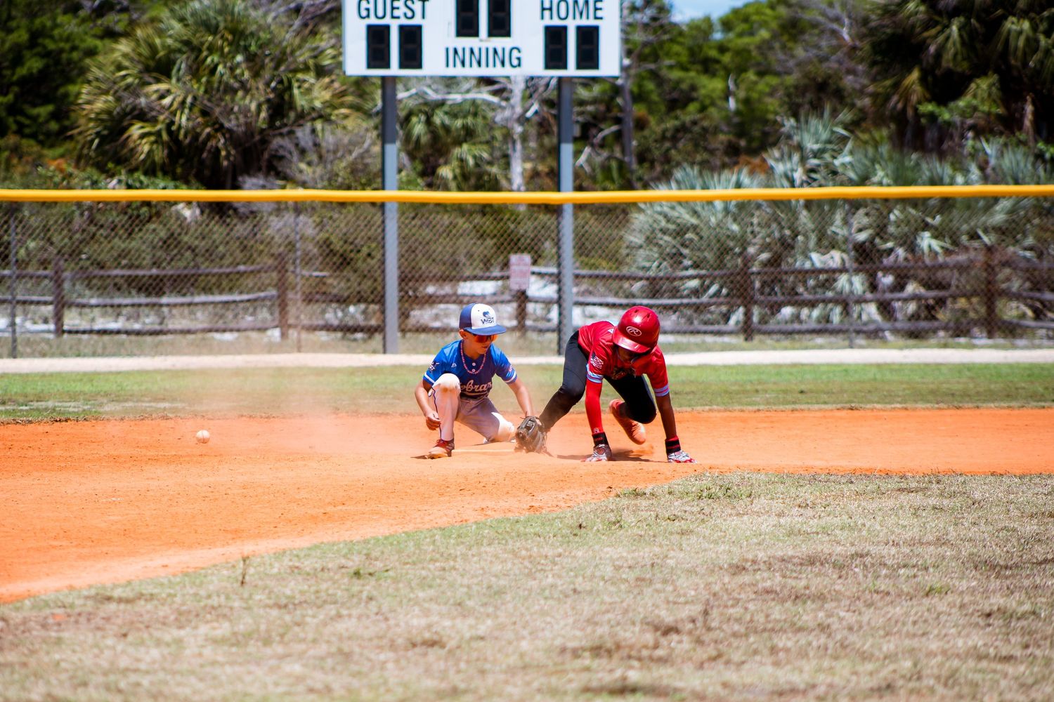 Baseball diamond with white building visible beyond outfield as players compete during game.