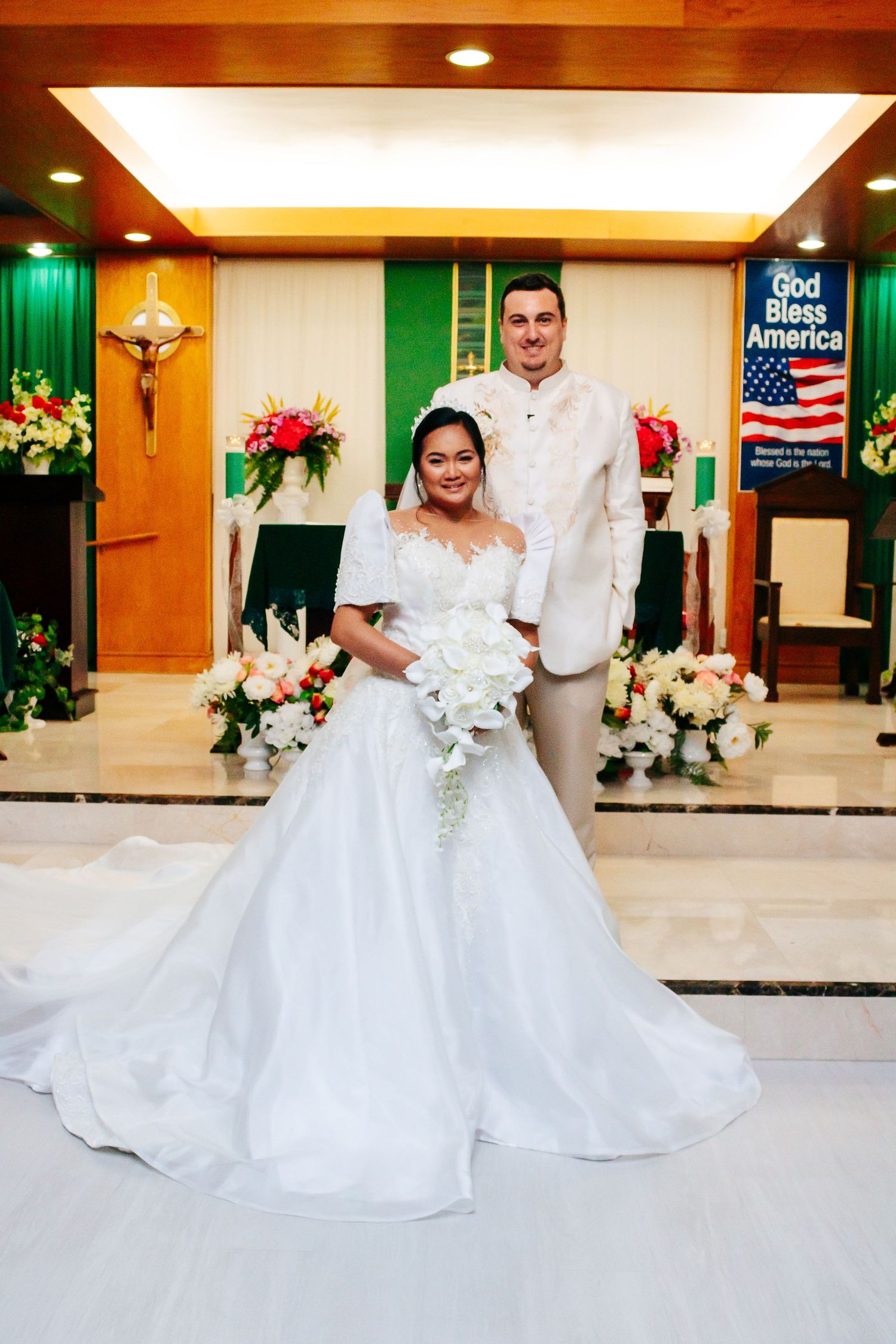 A detailed view of a bride's white ballgown wedding dress on a marble church floor.