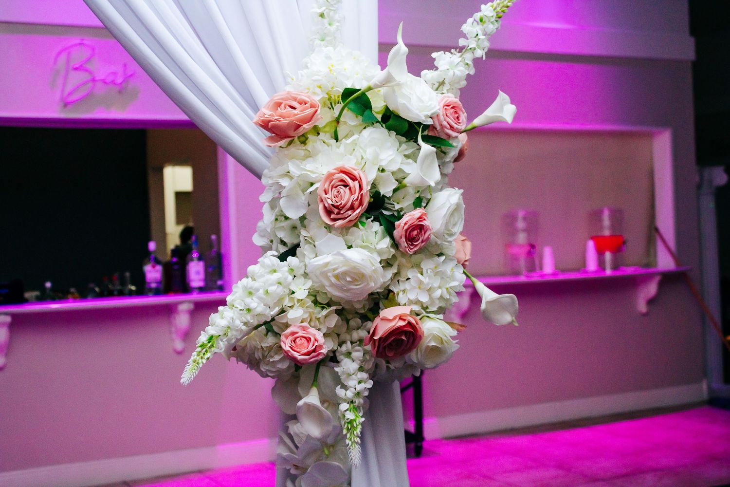 Elegant white and pink floral centerpieces with orchids against purple-lit reception backdrop.