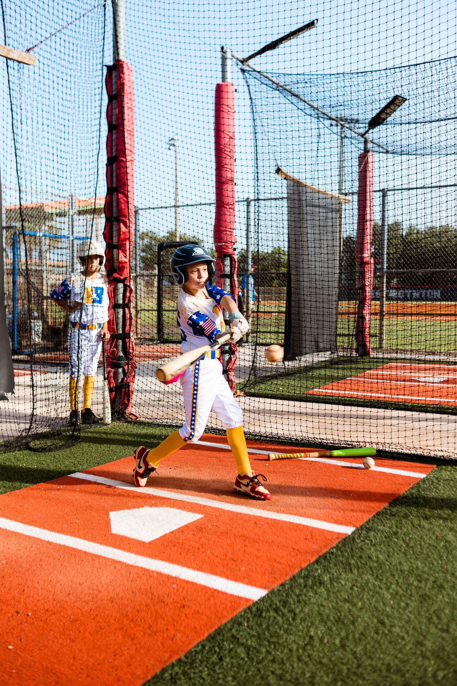 Baseball player demonstrates batting stance progression in sequential photos at indoor batting cage facility.