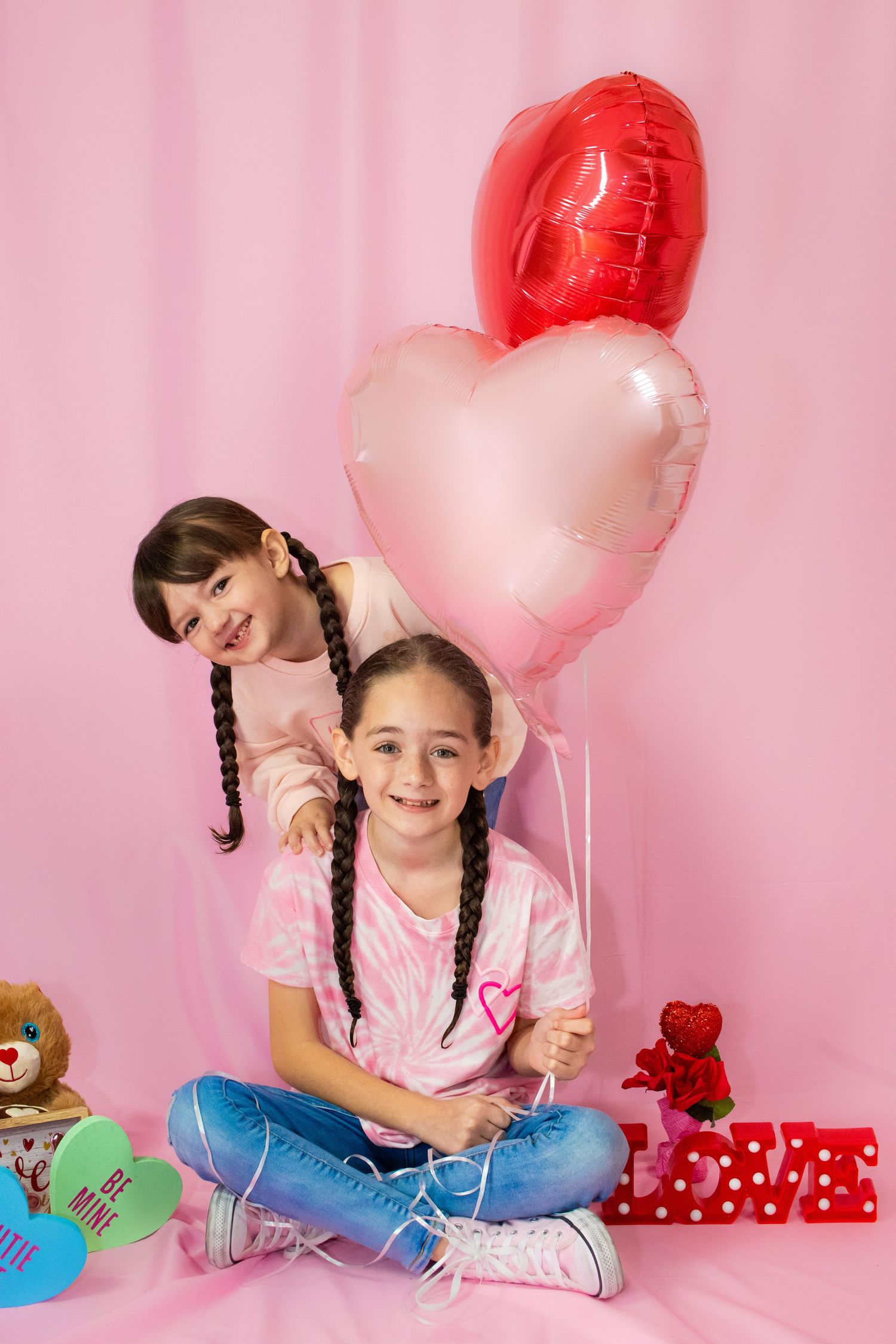 Sweet Valentine's themed photo with heart balloons and teddy bears on pink backdrop.