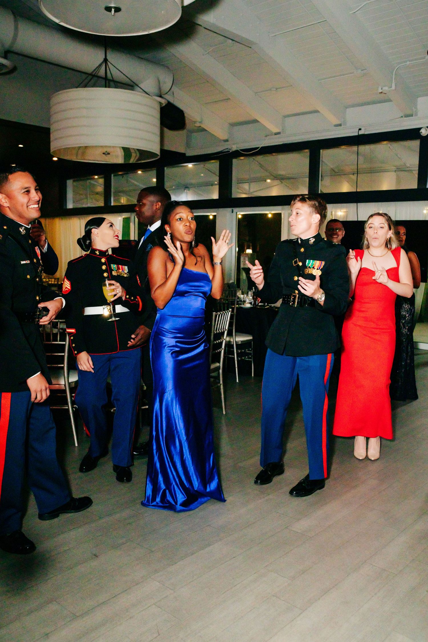 Military members and guests in formal attire socialize during an evening celebration.