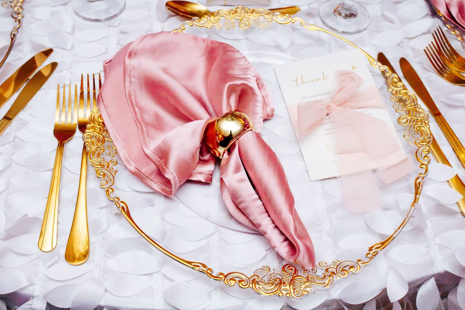 Elegant table settings with pink napkins and gold-rimmed plates.