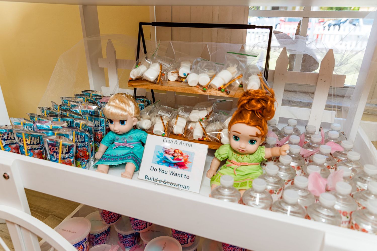 Party favor display featuring Disney princess dolls and packaged treats on white shelving.