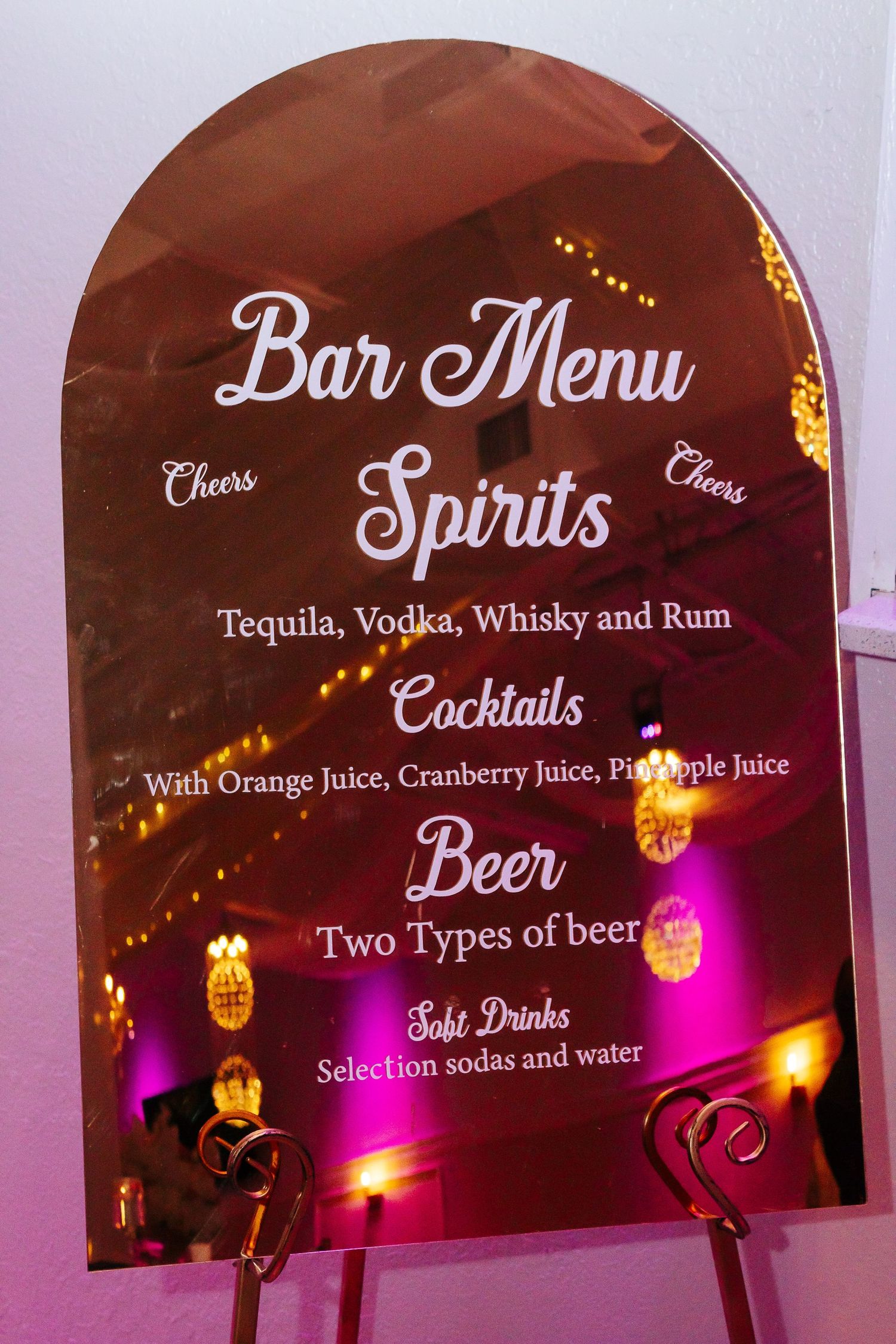 Elegant bar menu display listing spirits and cocktails in white script on burgundy background.