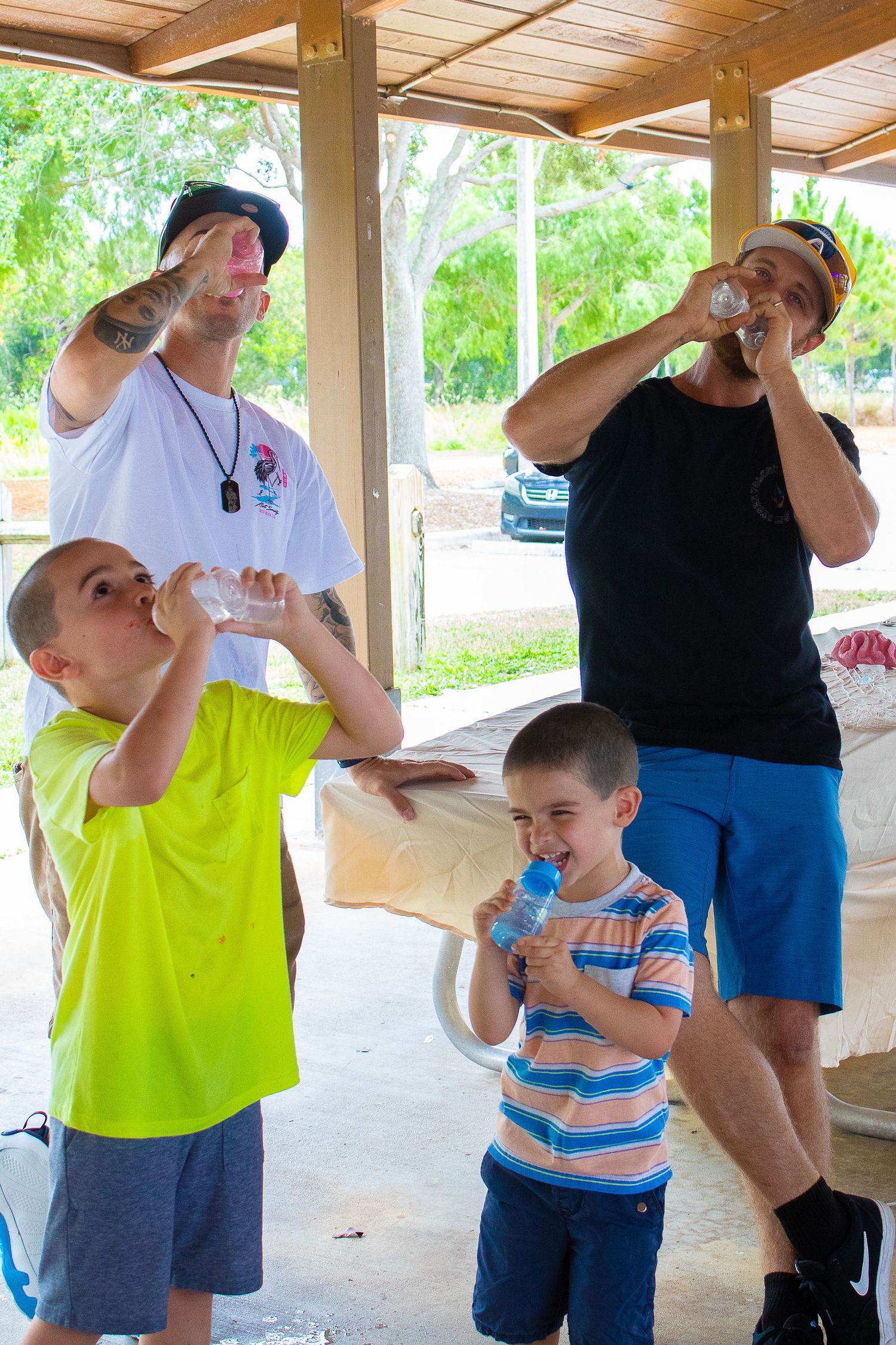 Group enjoying drinks together at outdoor gathering under covered pavilion.