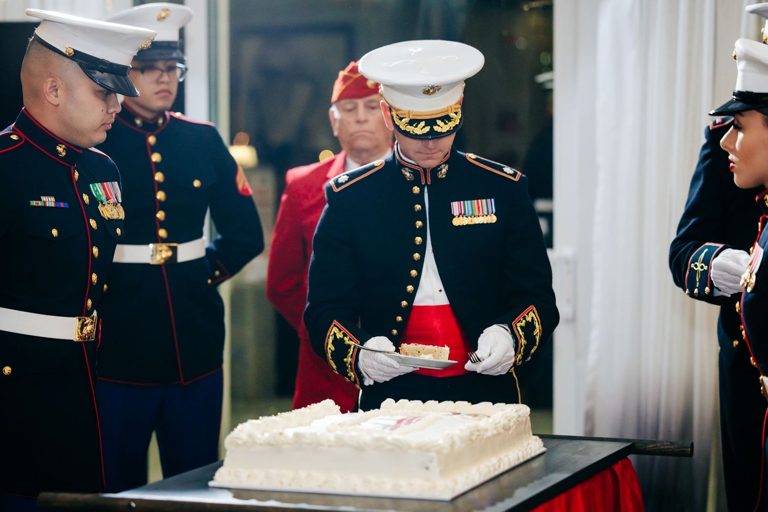 Military personnel and guests mingling around a decorated cake table at a formal celebration.