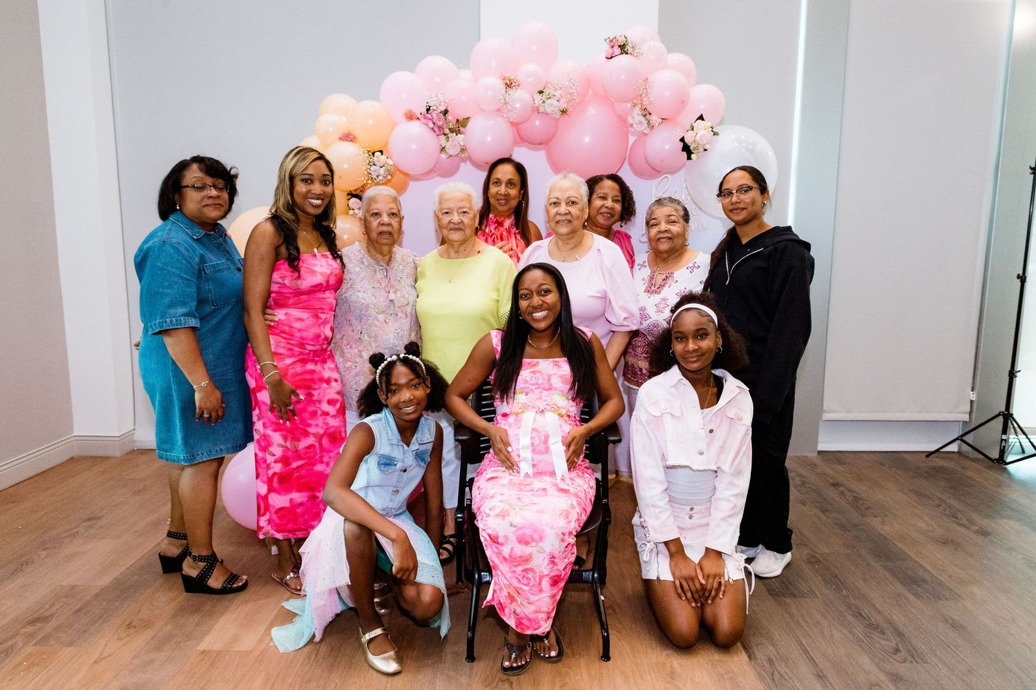 Pink balloon arch decorates a party space where guests gather for a celebration.